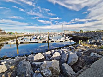 Sailboats moored at harbor against sky