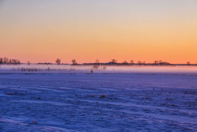 Scenic view of frozen lake against sky during sunset