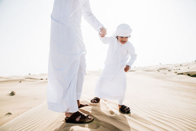 Low section of father with son enjoying while standing in desert
