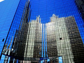 Low angle view of skyscrapers against blue sky