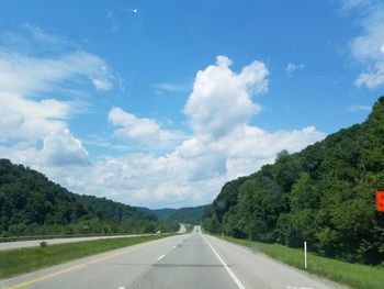 Road by trees against sky