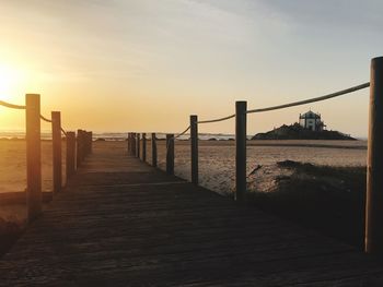 Pier over sea against sky during sunset