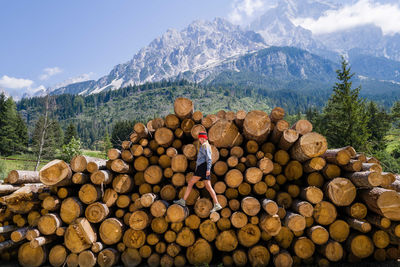 Woman standing on the stack of the tree logs
