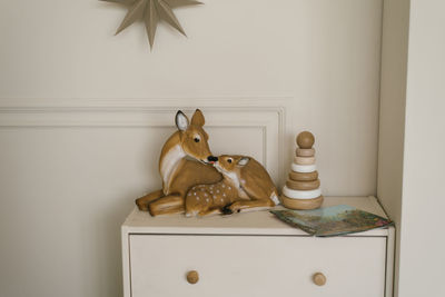 Deer figurines and a wooden toy pyramid for children on the chest of drawers in the interior