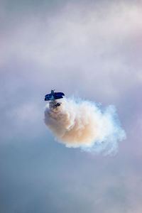 Stunt biplane at airshow pulls up suddenly into the sky leaving a large white vapor trail behind
