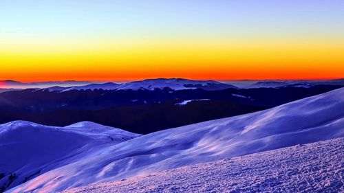 Scenic view of snowcapped mountains against clear sky during sunset