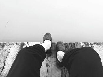 Low section of man standing on retaining wall against sea