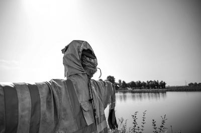 Rear view of man statue by lake against clear sky