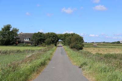 Road amidst field against sky