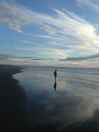 Silhouette man on beach against sky during sunset