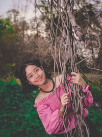Portrait of smiling girl while holding vines of tree