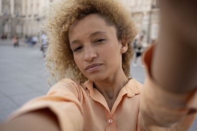 Latin young woman enjoying taking selfie with smartphone while visiting in madrid city