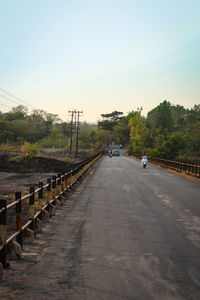 Road amidst trees against clear sky