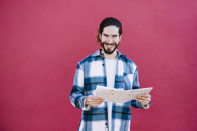 Portrait of a smiling young man against red background