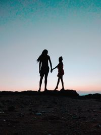 Silhouette friends standing on street against sky during sunset