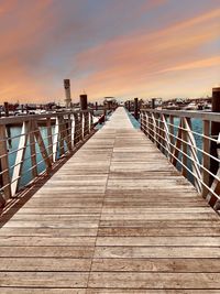 Surface level of pier over sea against sky during sunset