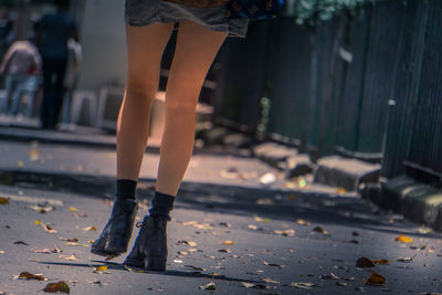 Low section of woman standing on footpath