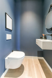 Stylish interior of bathroom with white ceramic sink and wall mounted toilet in minimal style