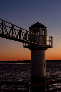 Pier over sea against sky during sunset