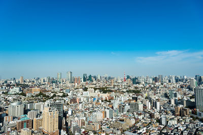 Aerial view of buildings in city against blue sky