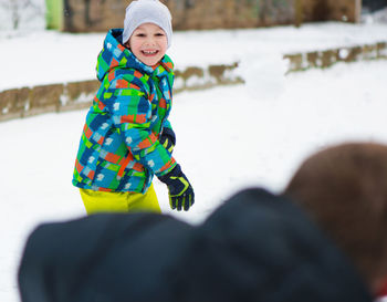 Boy throwing snow while standing in snow outdoors