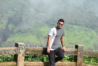 Portrait of smiling young man standing on mountain