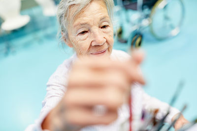 Close-up of senior woman holding paintbrush while sitting in nursing home