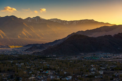 Aerial view of townscape and mountains against sky