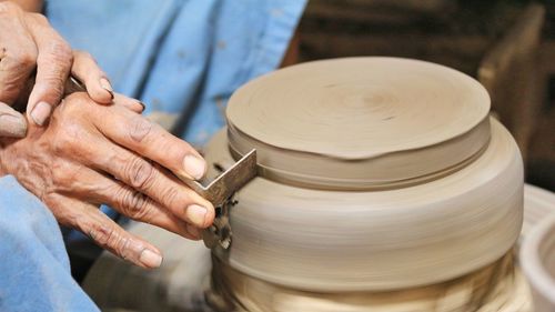 Midsection of man molding shape on pottery wheel