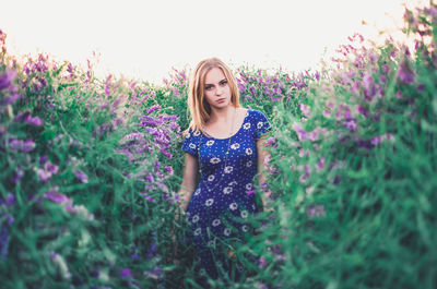 Portrait of beautiful young woman standing on field