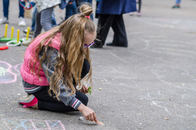 Side view of girl chalk drawing at playground