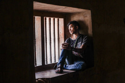 Young man looking away while sitting at home