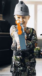 Boy holding toy while standing at home