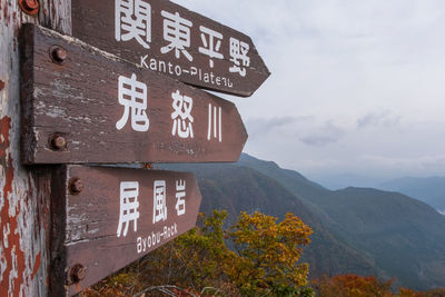 Information sign on mountain against sky