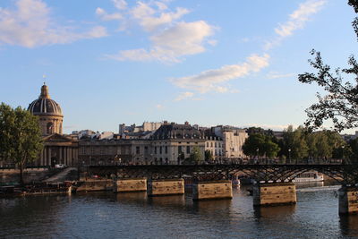 Buildings at waterfront against cloudy sky