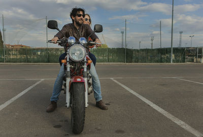 Couple riding motorcycle on road against sky