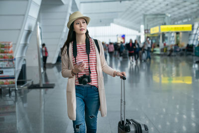 Woman standing with umbrella at airport