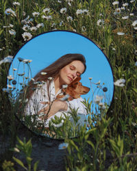 Reflection of woman with dog in mirror on grass