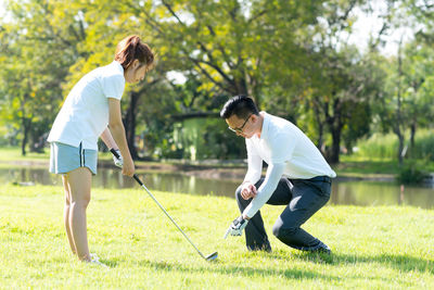 Full length of couple playing golf on field