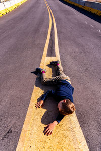 High angle view of boy lying on road