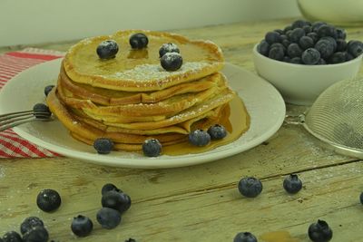 Maple syrup and fresh blueberries on pancakes stack rustic wooden background. selective focus.