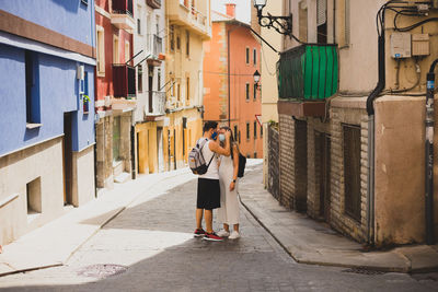 Rear view of people walking on street amidst buildings