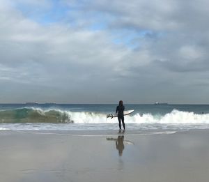 Full length of man standing on beach against sky