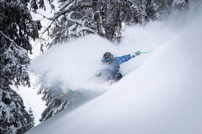 Man skiing on snowcapped mountain against trees