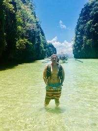 Man standing in sea against trees