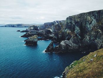 Scenic view of sea by rock formations against sky