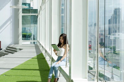 Woman using digital tablet while sitting in building