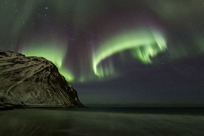 Scenic view of sea against aurora borealis at night