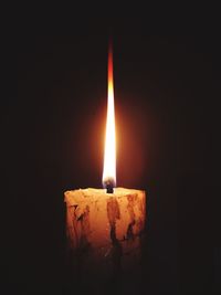 Close-up of lit candle in darkroom