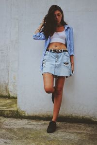 Portrait of young woman standing against wall